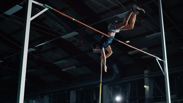 Pole Vault Jumping Championship: Professional Male Athlete Running with Pole Successfully Jumping over Bar. Determination of High Achievement Champion in Training. Aerial Shot in Slow Motion