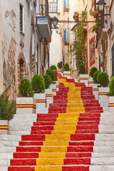 Picturesque stone street with spanish flag in Calpe. Alicante, Valencia