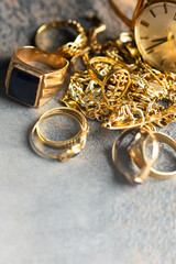 Old and broken jewelry , rings, chain, braclets, watch,  earrings on concrete background for Sell cash for gold concept.Copy space
