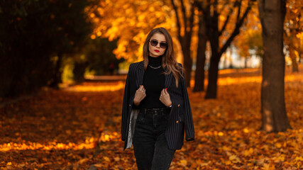 Fashionable beautiful girl with vintage sunglasses in trendy black clothes with a fashion blazer,...