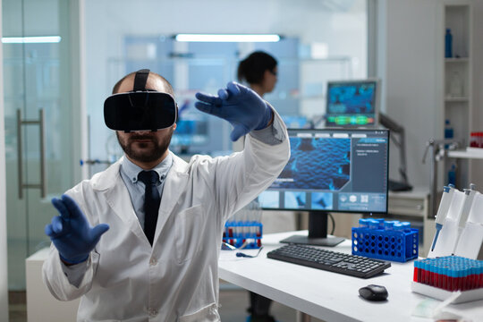 Chemist researcher analyzing sickness development using virtual reality headset during medical experiment in biochemistry hospital laboratory. Modern biotechnology equipment - Powered by Adobe