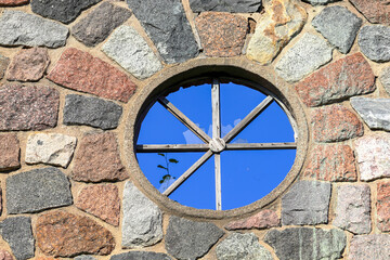 Fototapeta na wymiar Round window with broken glass in a stone wall