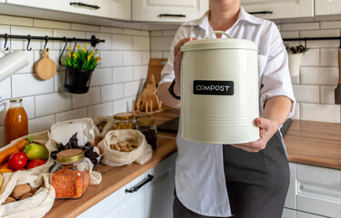 Adult woman holds a compost bin. Kitchen interior. Copy space. Waste sorting. Zero waste concept.