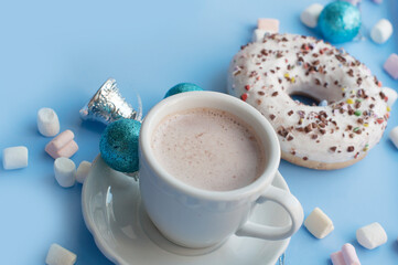 Christmas breakfast with white donuts, coffee, marshmallows and Christmas decorations on blue background