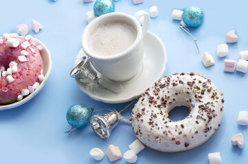 Christmas breakfast with white donuts, coffee, marshmallows and Christmas decorations on blue background