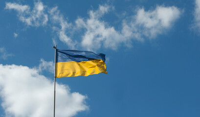 Ukrainian flag waving against a background of blue sky and white clouds