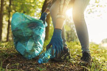 Young cleanup volunteer collecting trash in the forest - obrazy, fototapety, plakaty