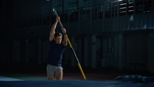 Pole Vault Jump Championship: Professional Male Athlete Running with Pole Successfully Jumping over Bar, Raising Arms, Celebrating. Determination, Motivation of Champion in Training. Slow Motion Shot