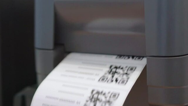 The black barcode printer is printing the QR code on the sticker.