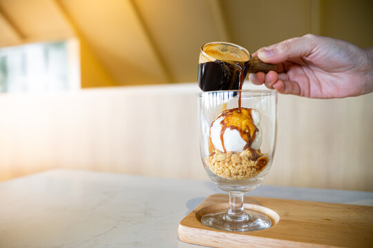 Pouring coffee on vanilla ice cream in a glass to make affogato coffee