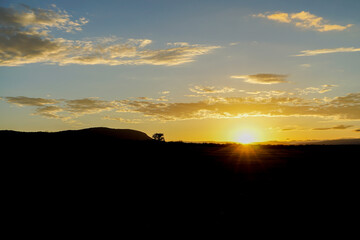 A landscape of rising savanna sunrises with gradations in the sky (Masai Mara National Reserve, Kenya)
