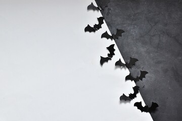 Halloween and decoration concept - black paper bats flying on gray and white background. Flat lay, copy space.