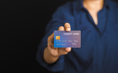 Hand of holding a mockup blue credit card while standing with a black background in the studio. Close-up photo. Money and business concept