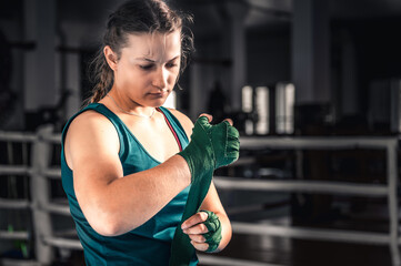 Young woman getting ready for boxing exercise. Woman boxer getting ready near the ring