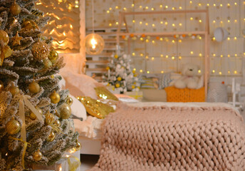 New Year's modern bedroom, nursery in a golden style. Christmas tree on the background of the bed, toys on the background.Beautiful blur garlands. Beautiful Christmas interior