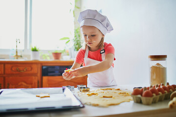 Adorable preschooler girl making cookies