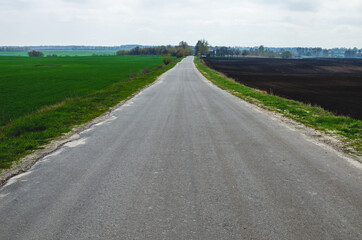 Empty asphalt road leading to the village