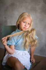 Naklejka premium Portrait of a girl, there are many interesting emotions on her face. Great for demonstrating the character of a child - thoughtfulness, daydreaming, aspiration, growth, thoughts, smile. Background gra