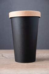 empty black cardboard glass with a lid stands on table with gray background. closeup and place for text