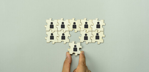 Top view of human resources and recruiting business or team leader concepts. Hand adult Asian man holding of people icon community on wooden cube block. Object on grey paper background. Banner border.