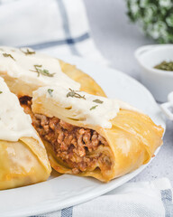 Slice of omemade lasagna with cheese cream in high key composition 