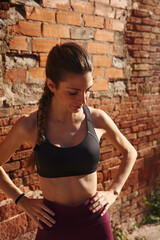 Woman looks down as she stands next to a wall