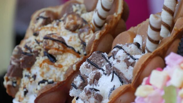 Sweet bubble Hong Kong waffles with marshmallows, chocolate, candies and marmalade on the counter of a candy store