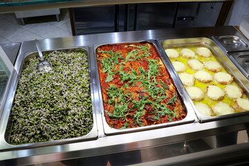 Typical Italian foods ready for purchase in an Italian take-away deli. Spelled and pea salad,...