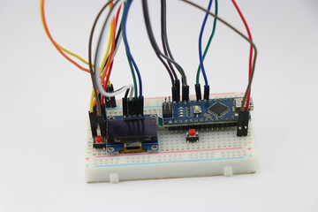 Breadboard circuit made from display module and microcontroller board connected with wires shows...