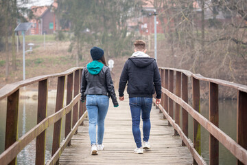 Young couple walking on an old wooden bridge on a foggy winter day at Lake Gebart in Zalaegerszeg, Hungary