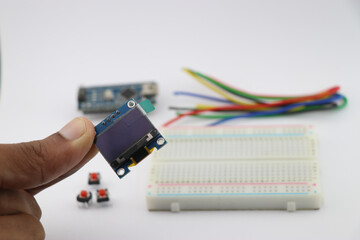 Young inventor holding OLED display in hand, Arduino display module with breadboard and wires on...