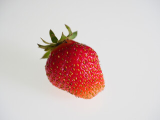 A single healthy colourful strawberry in closer on a white background