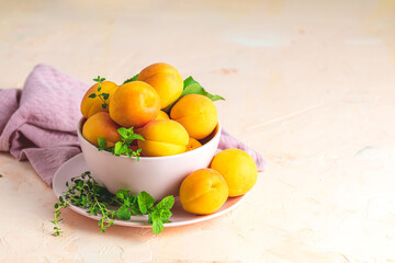Fresh sweet yellow orange apricots in pink bowl on the pink concrete surface table