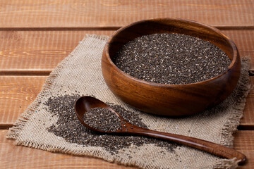 Chia seeds in a bowl with a wooden spoon on a natural wooden background. Rustic style.
