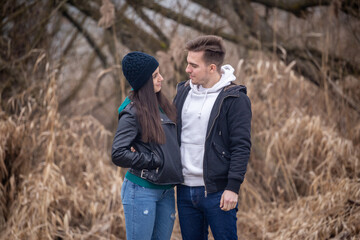 Young couple standing in nature on a winter day, looking at each other