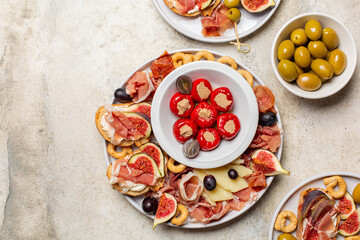 Mediterranean style appetizers and charcuterie board. Bruschetta with prosciutto and figs, cheese, olives, preserves. Light background, directly above, copy space.