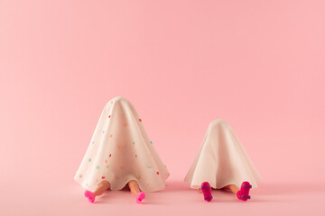 Two girls in white ghost costume with rollers and high heels on pink background.. Creative ...