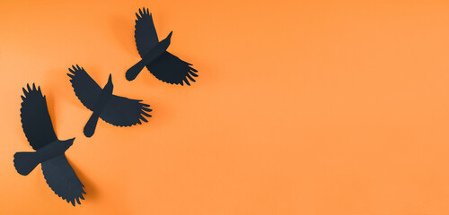 Three black crows on an orange background.