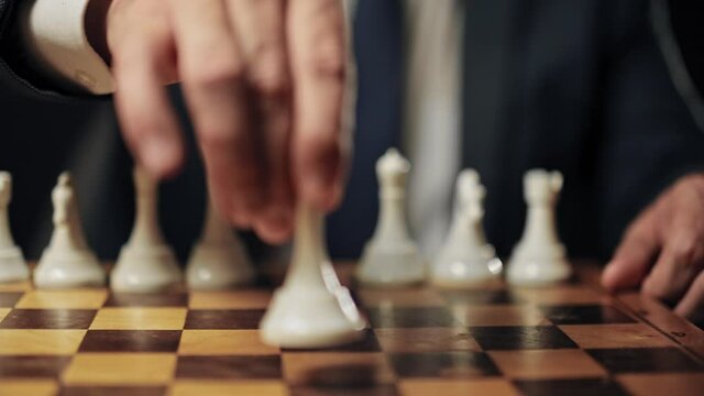 Assertive man moving queen piece along chessboard, business strategy, planning