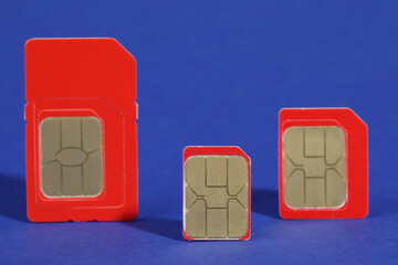 Different red SIM cards on blue background, closeup