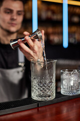 Bartender in apron adds ingredient to glass