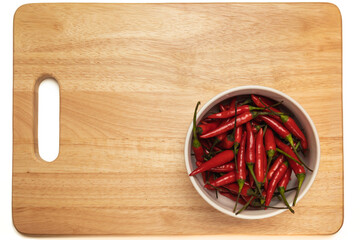 Red chili pepper in a bowl on a wooden cutting board