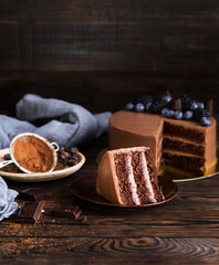 Festive chocolate cake. Cake for the party. Cocoa and chocolate pieces. A piece of cake on a plate. Birthday. Delicious dessert