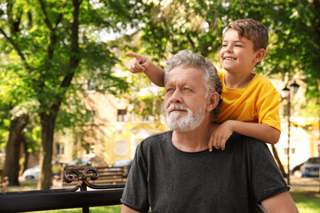Obraz premium Senior man with his little grandson resting together in park