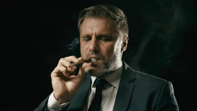 Businessman smoking cigar, thinking over business strategy, smoke in slow motion