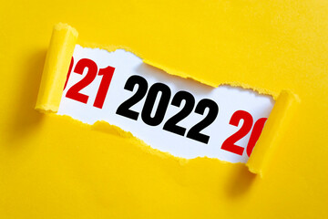 Yellow package paper torn to reveal white panel New year 2022