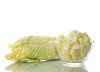 One ripe fresh Chinese cabbage and shredded cabbage in a glass bowl, close-up, isolated on white.