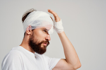 male patient with bandaged head and eye hospitalization light background