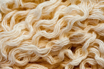 Close-up shot of a skein of beige woolen thread.