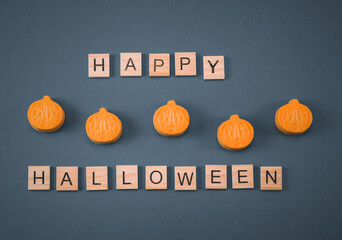 Chocolate pumpkins and wooden cubes on a gray background.